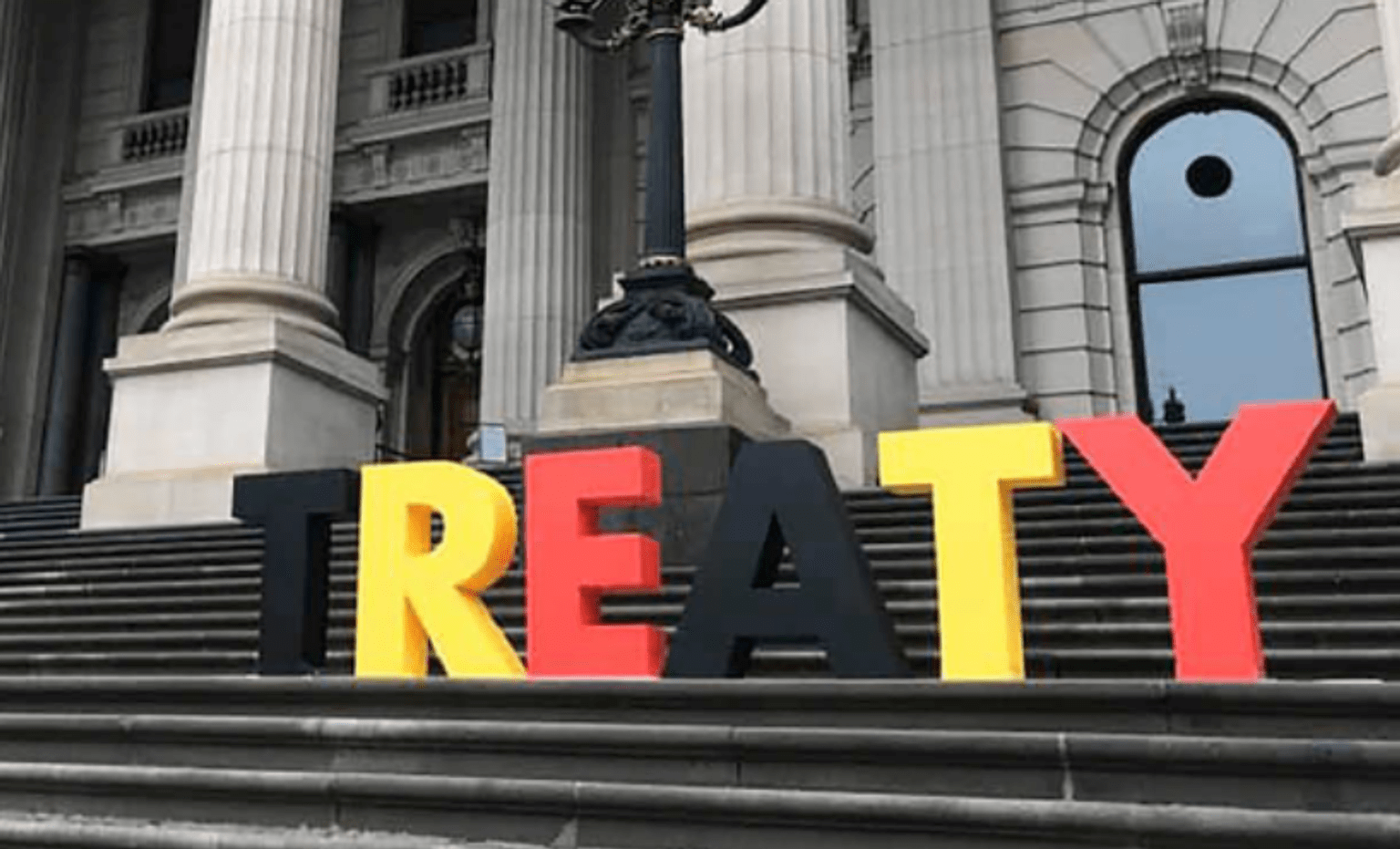 Letters in black yellow and red spelling out Treaty on the steps of Parliament House