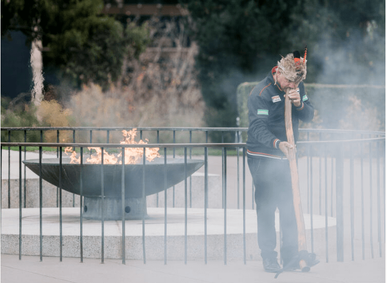 Eternal flame with smoke surrounding Uncle Ron Murray playing didgeridoo